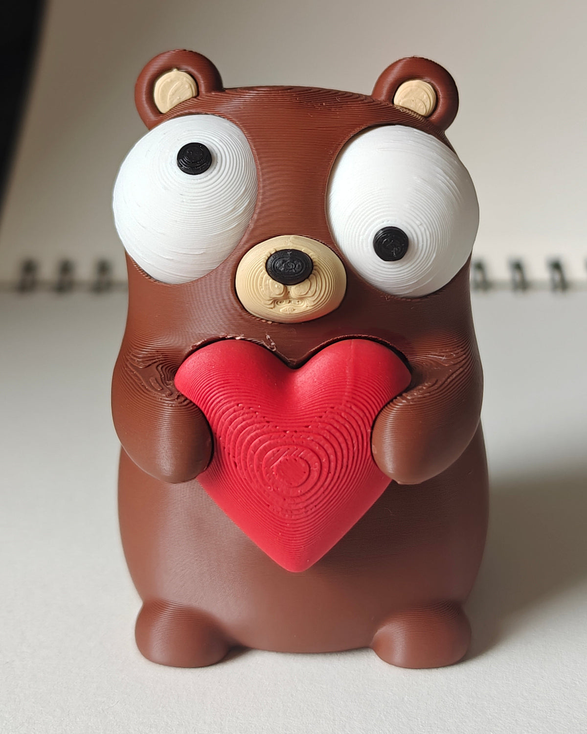 Närbild av en liten björnfigur med hjärta och stora rörliga googlyögon