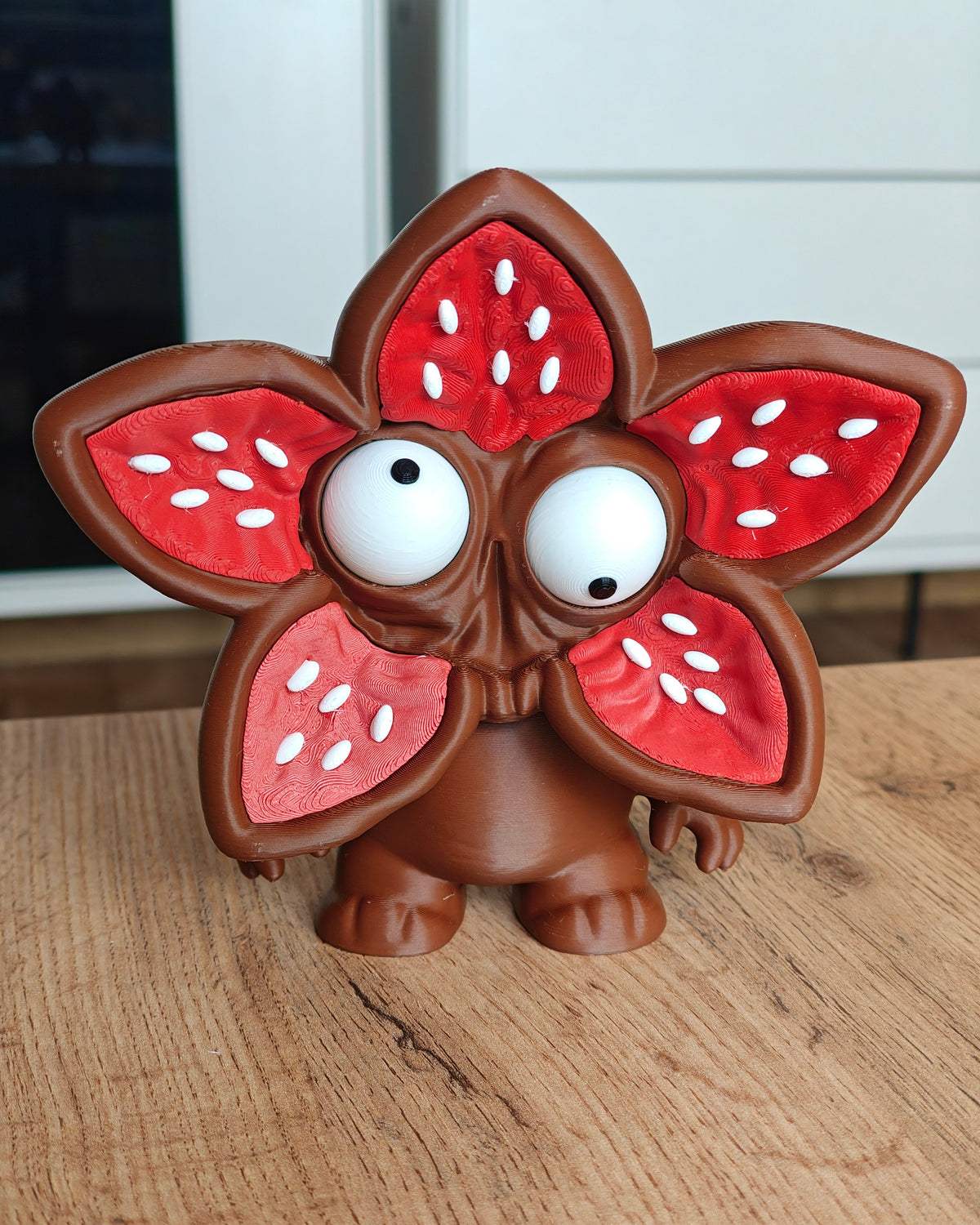 Monsterfigur med blomansikte och stora rörliga ögon, framifrån