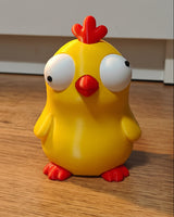 Närbild av en rolig kycklingfigur med stora rörliga googlyögon mot vit bakgrund