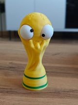 Närbild av en rolig VM-pokalfigur med ett stort rörligt googlyöga, framifrån