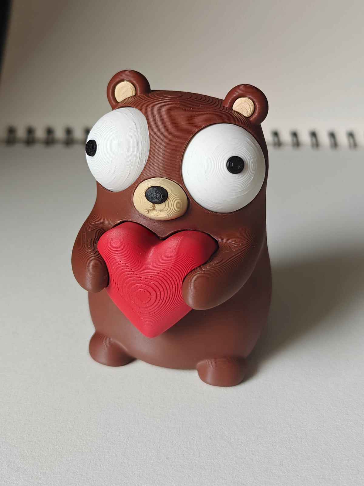 Närbild av en liten björnfigur med hjärta och stora rörliga googlyögon