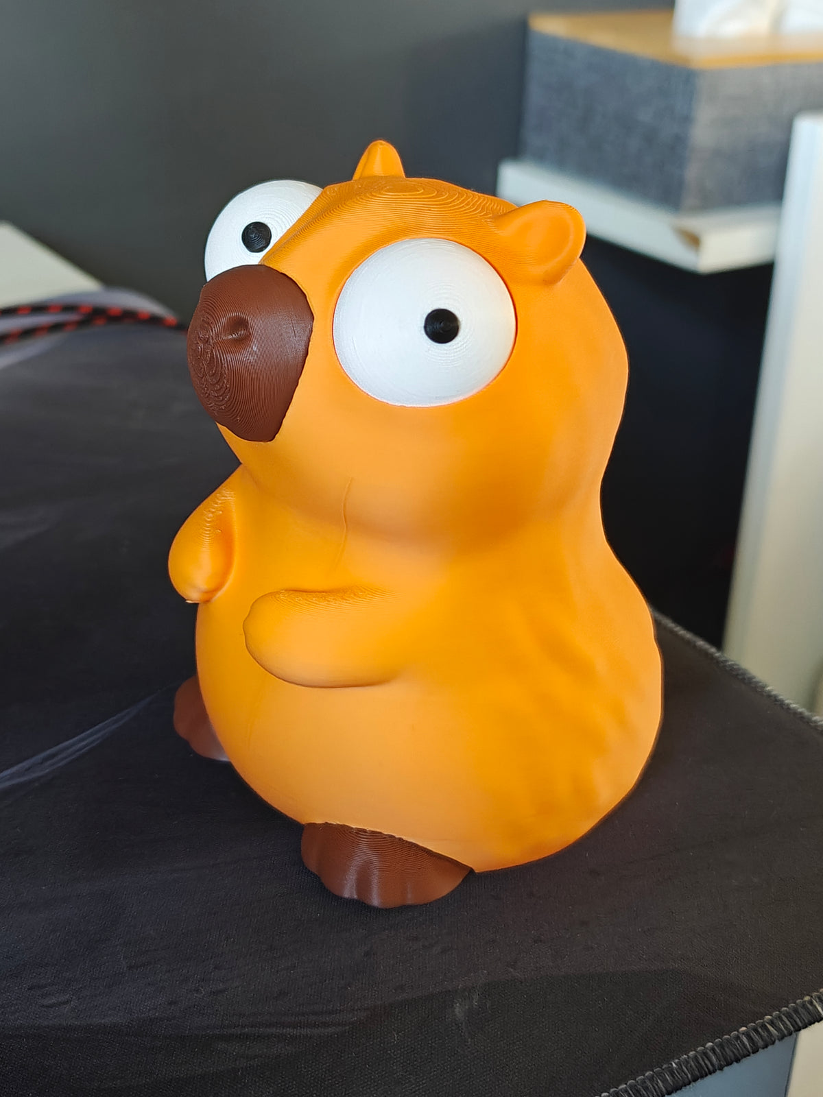 Kapybarafigur med stora rörliga googlyögon, framifrån mot vit bakgrund