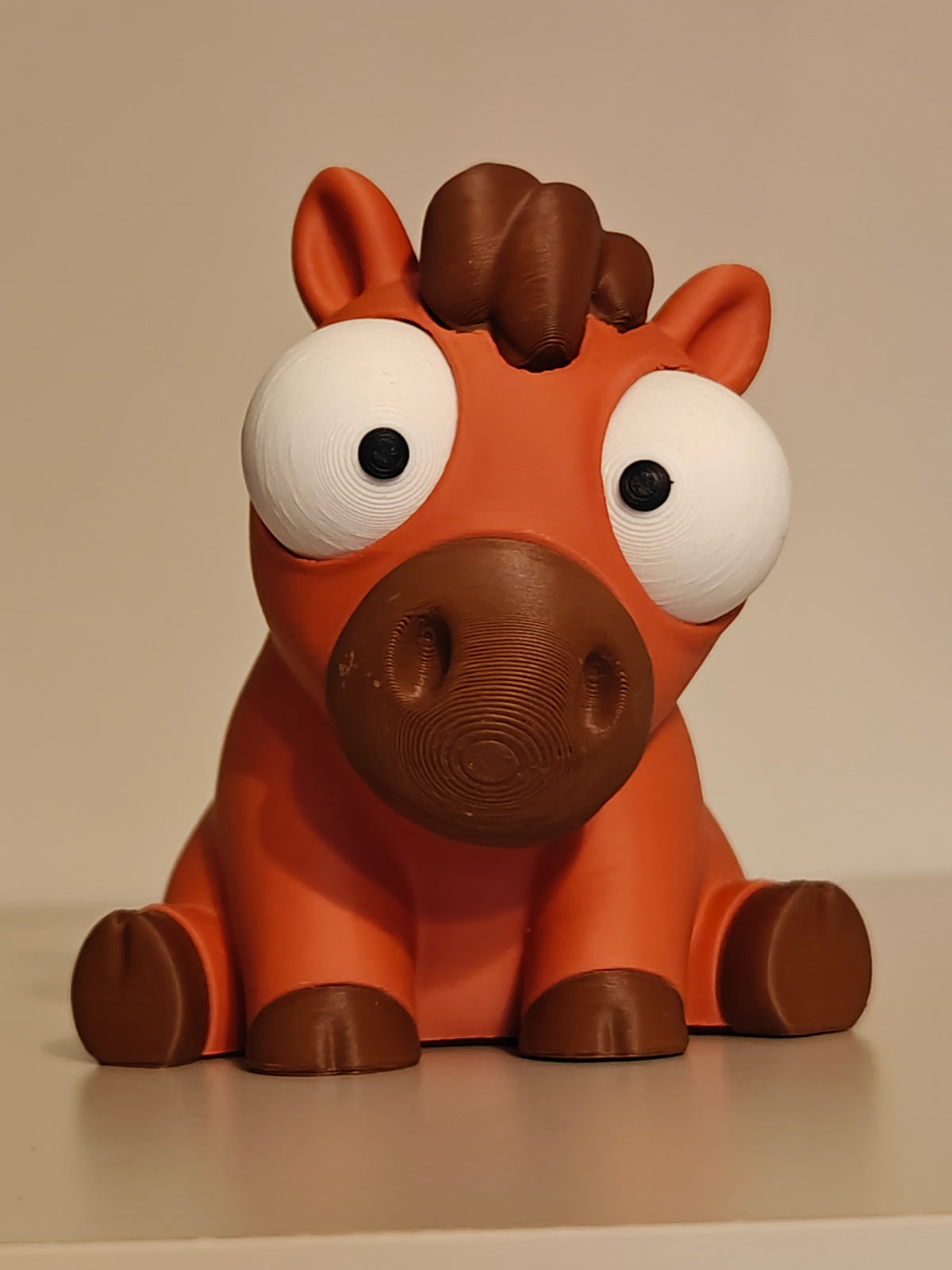 Närbild av en rolig hästfigur med stora rörliga googlyögon på vit yta