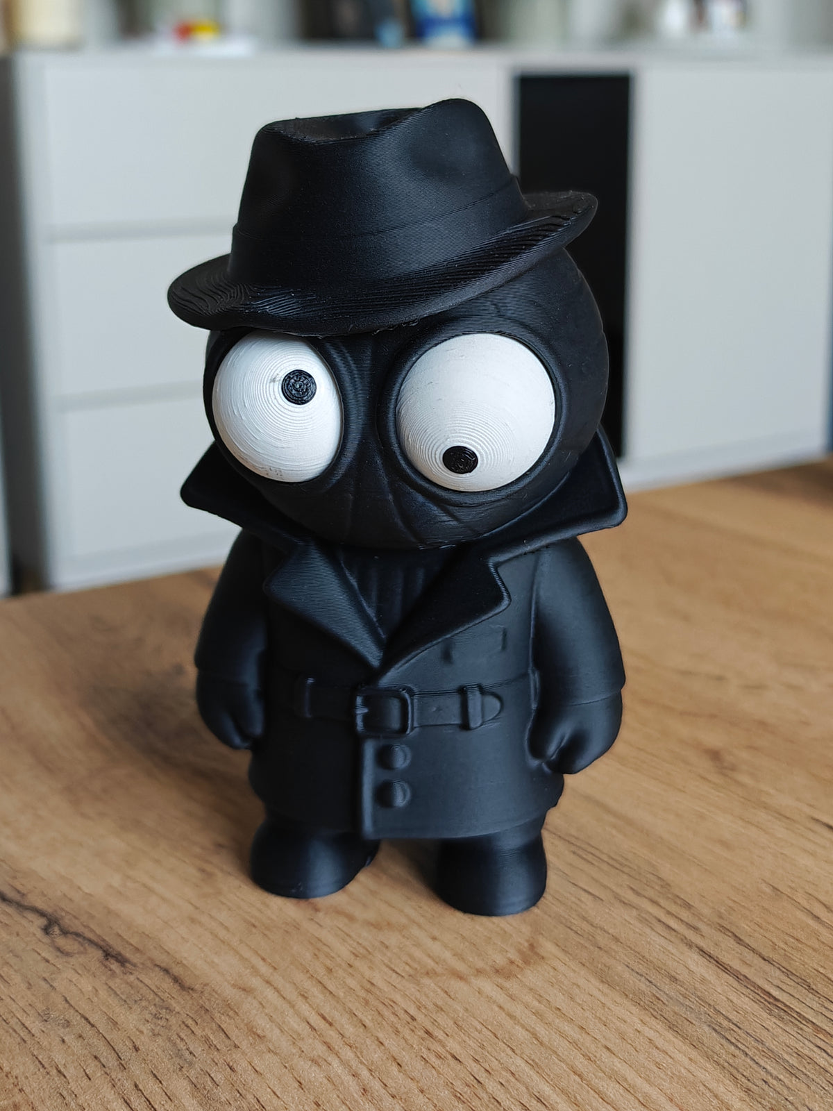 Spider Noir-figur med rörliga ögon, mörk rock och hatt, närbild mot vit bakgrund
