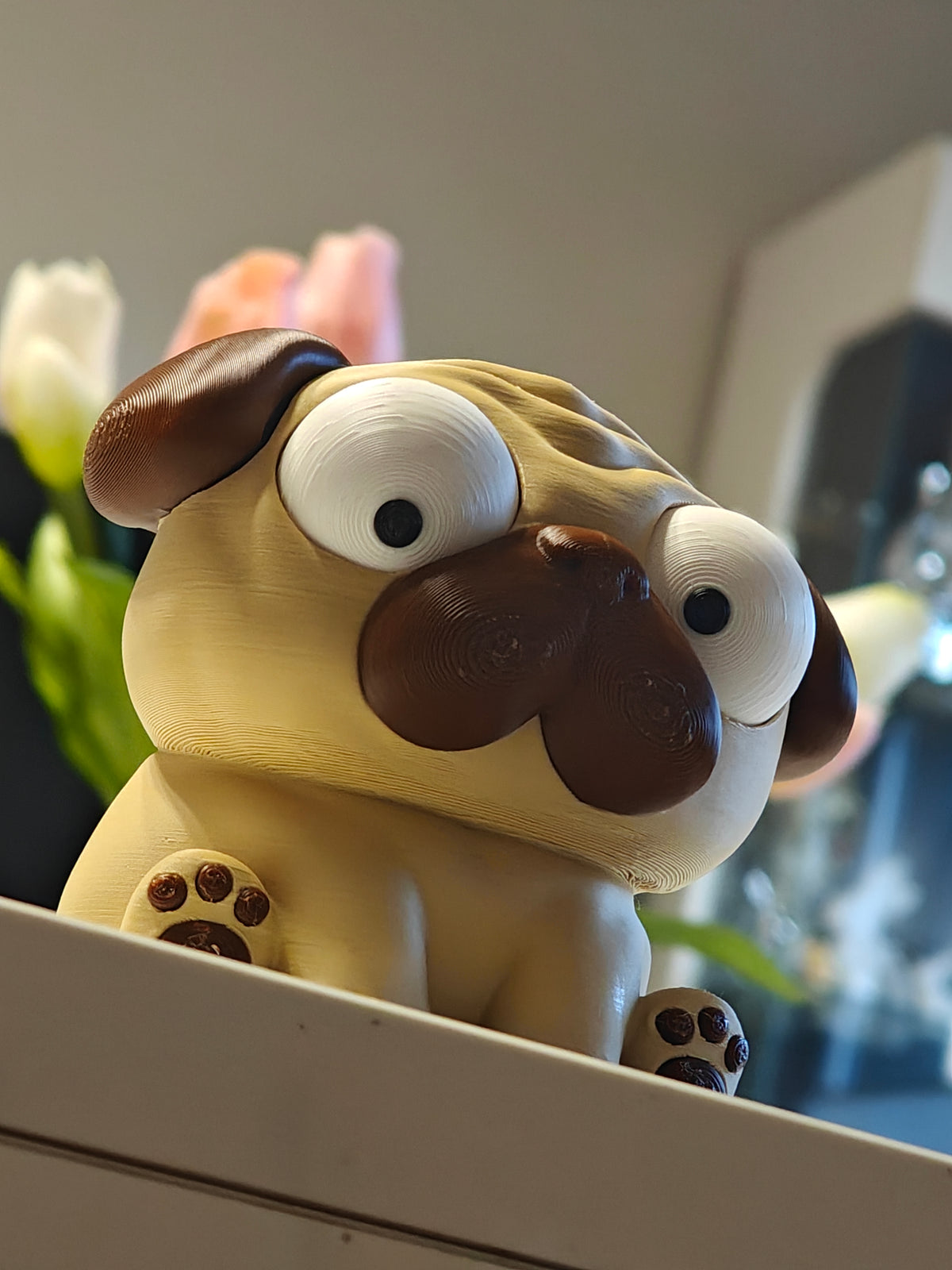 Mopsfigur med rörliga ögon mot vit bakgrund – Puggy-skrivbordsleksak