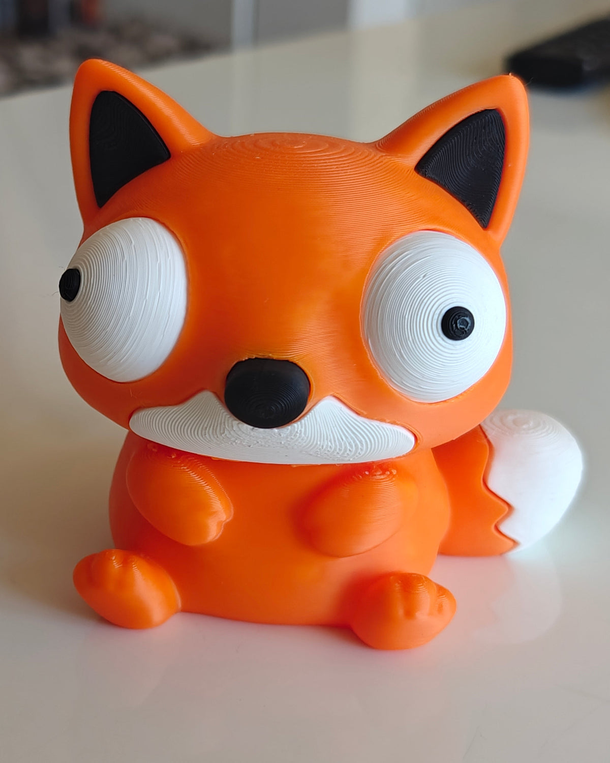 Foxie-rävfigur på skrivbord bredvid växt och kaffemugg