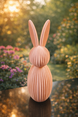 Påskhare på en hyllkant bland blommor och vårdekorationer