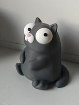 Tokig kattfigur med rörliga ögon på skrivbord bredvid kaffemugg