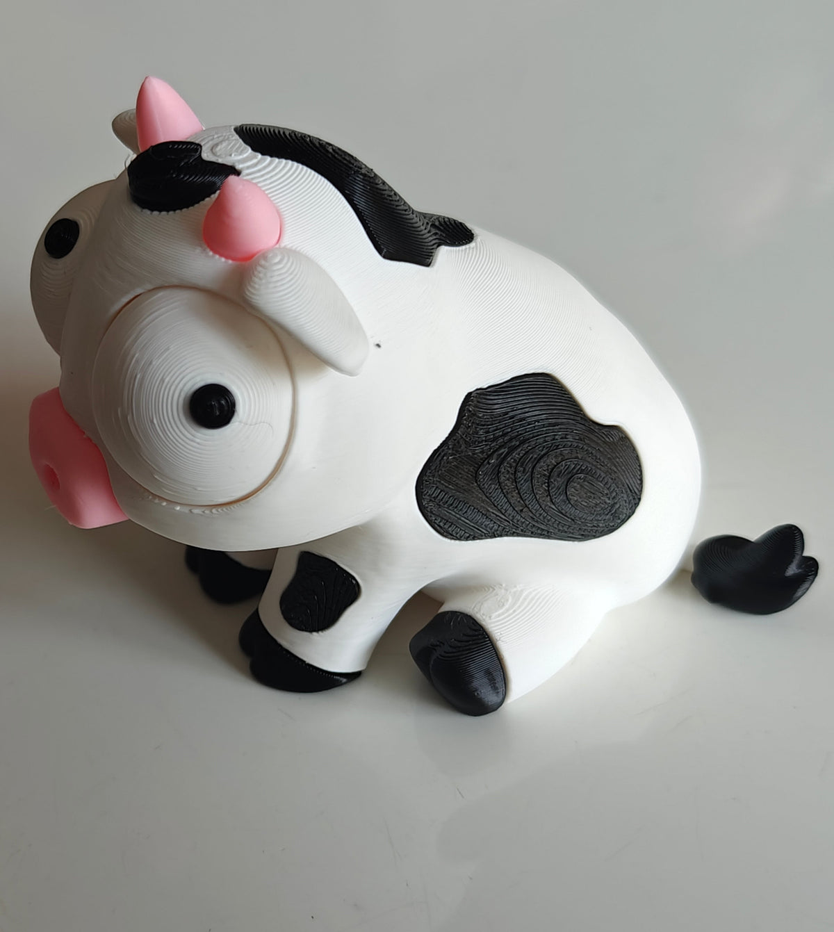 Närbild av en rolig vit och svart kofigur med stora rörliga googlyögon
