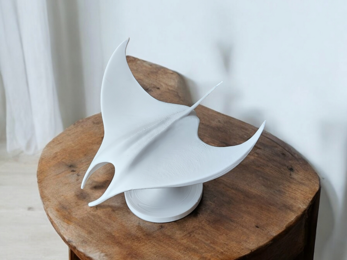 Minimalistisk skulptur av en mantarocka på en ljus trähylla mot en vit vägg
