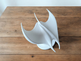 Närbild av mantarockeskulpturens släta vita yta och bakåtsvepta vingar