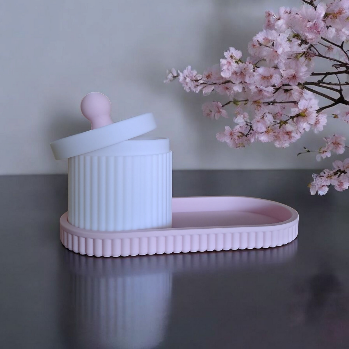Närbild av en räfflad smyckesburk med lock och matchande bricka i rosa och vitt