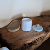 Närbild av en räfflad smyckesburk med lock och matchande bricka i rosa och vitt