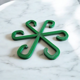 Närbild av en minimalistisk växtstödskrok i neutral färg mot vit bakgrund