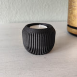 Minimalistisk värmeljushållare med tänt LED-värmeljus på en trähylla