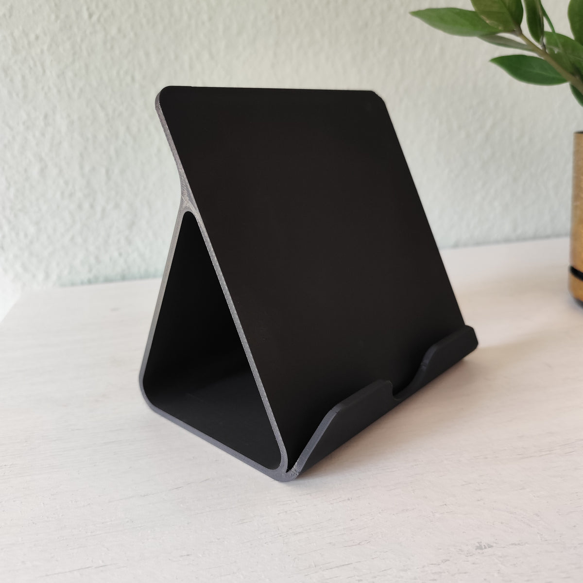 Surfplatta i iPad-ställ på ett städat skrivbord bredvid kontorstillbehör