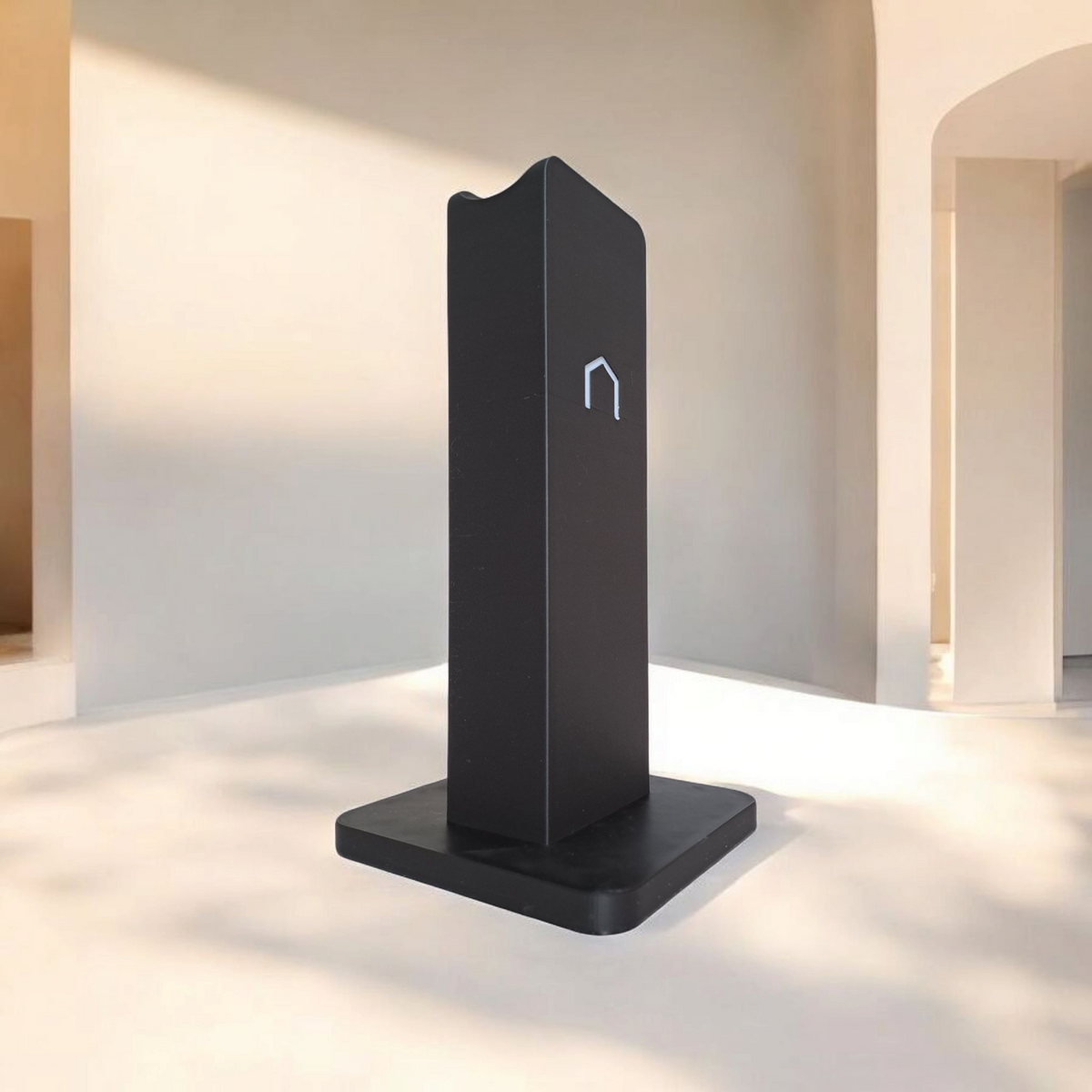 Närbild av loggan på framsidan av en modern minimalistisk hörlurshållare