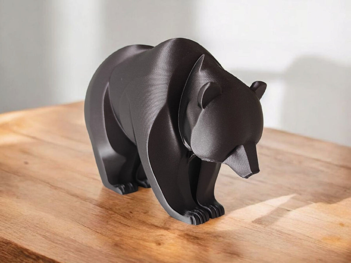 Närbild av en minimalistisk björnskulptur med böjda linjer och slät yta