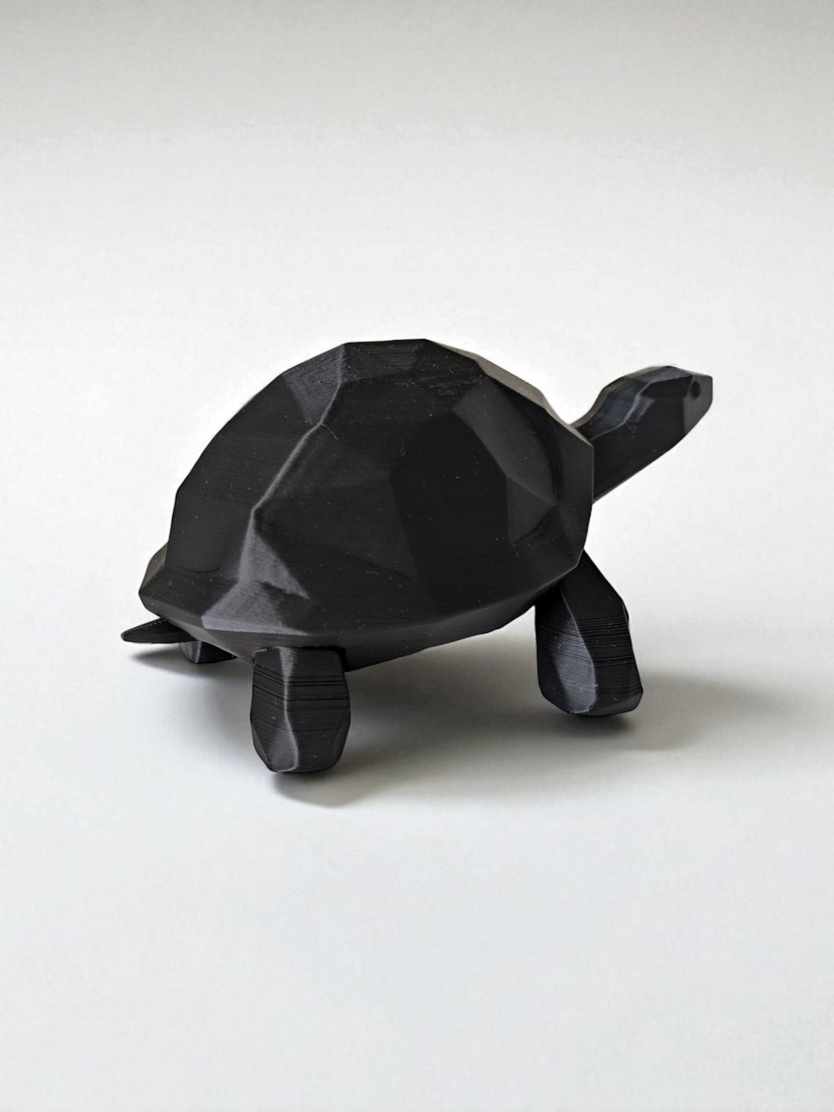 Närbild av en low poly-sköldpaddsskulptur med fasetterad yta och rena linjer