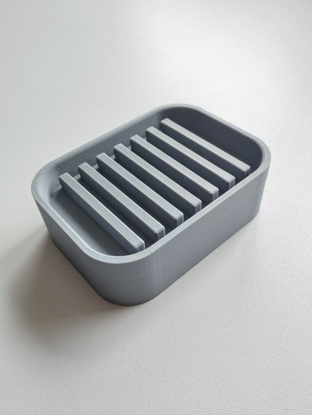 Detalj av minimalistisk tvålhållare med dräneringslutning och fin kant