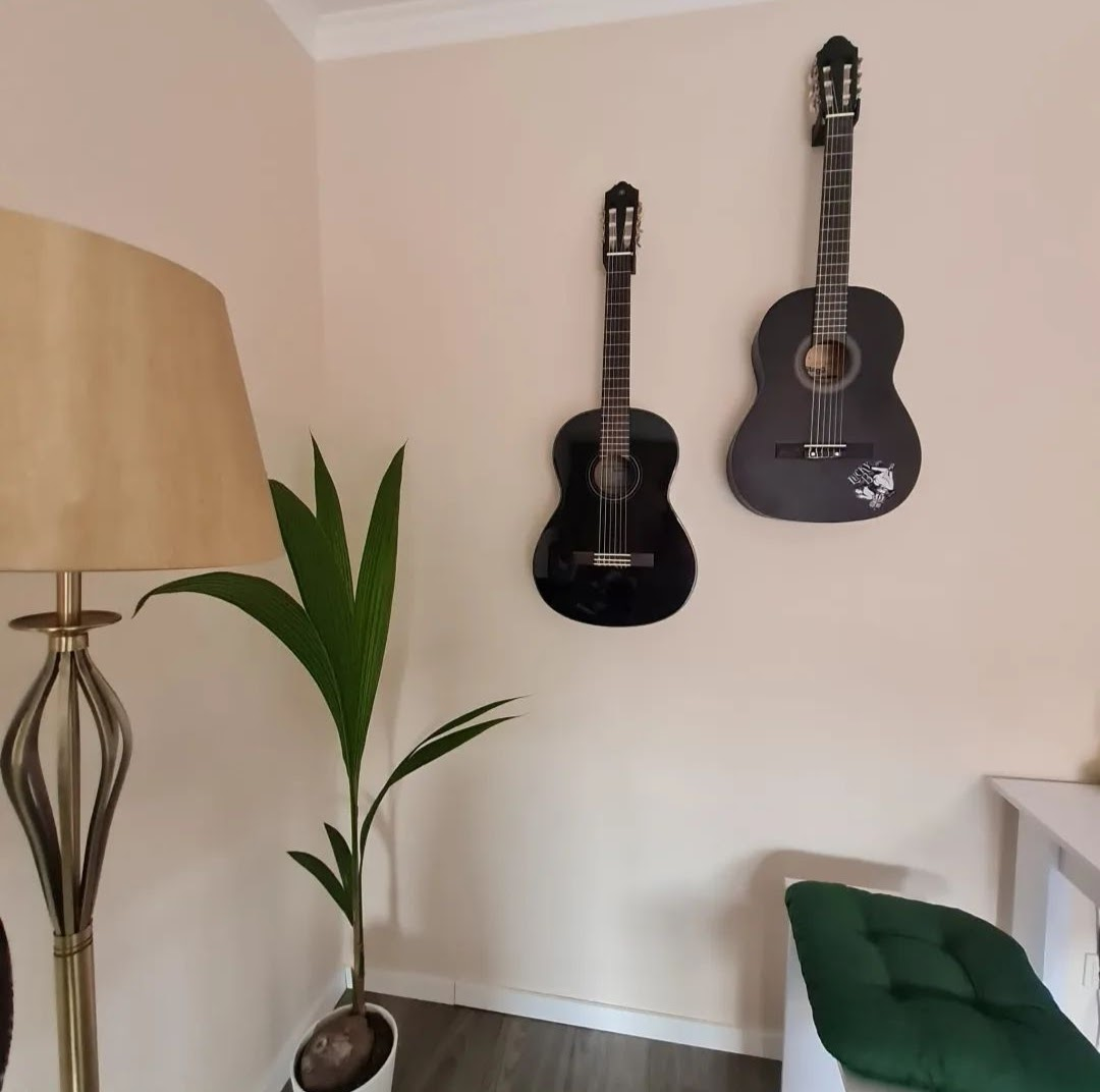 Elgitarr på vit vägg i diskret minimalistisk hållare