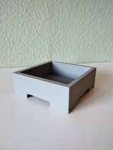 Minimalistisk bonsaikruka med en liten växt på en ljus trähylla