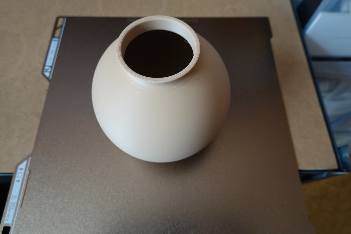 Närbild av en minimalistisk rund vas med slät klotform