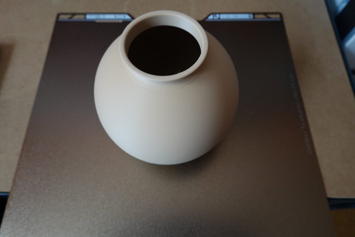 Närbild av en minimalistisk rund vas med slät klotform