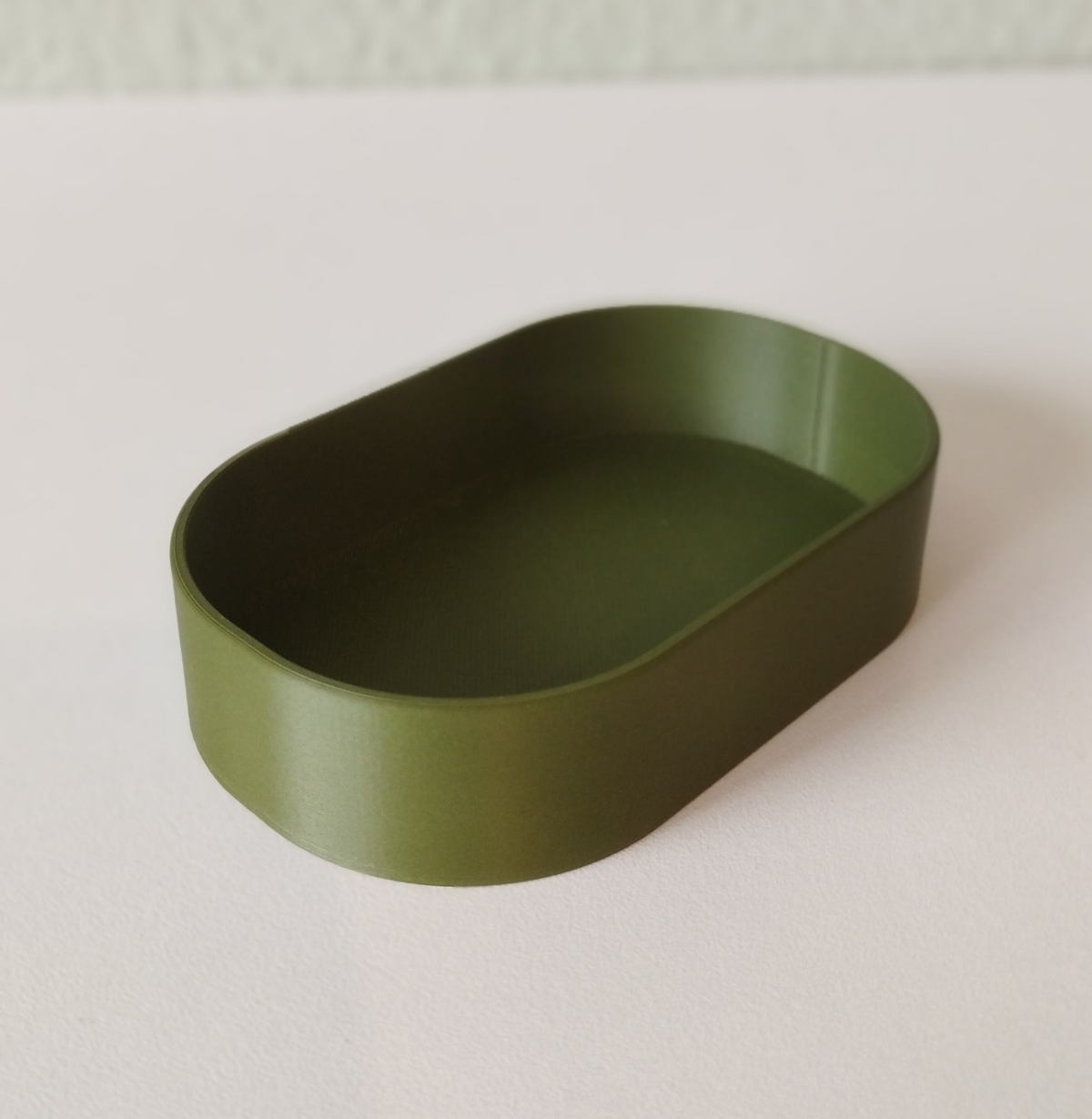 Minimalistisk rund nyckelbricka i mjuk neutral ton, närbild av den släta, plana ytan