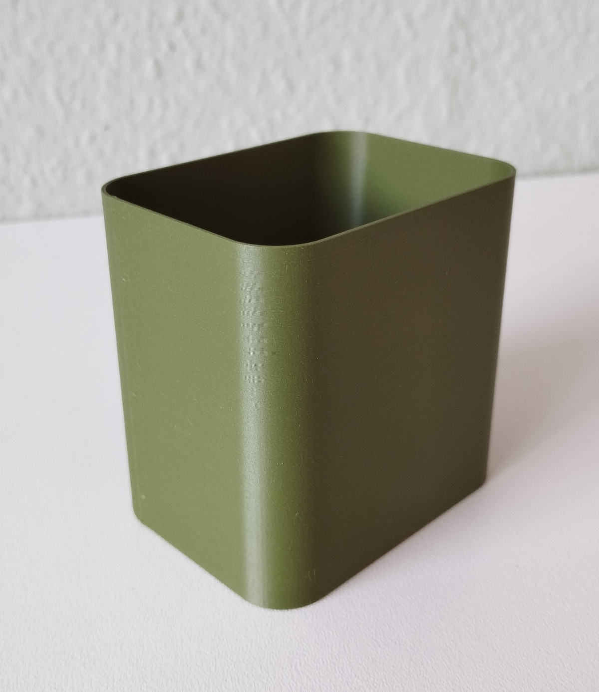 Minimalistisk pennhållare på ett skrivbord med pennor och anteckningsböcker