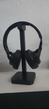 Hörlursställ på skrivbord bredvid skärm och skrivbordslampa