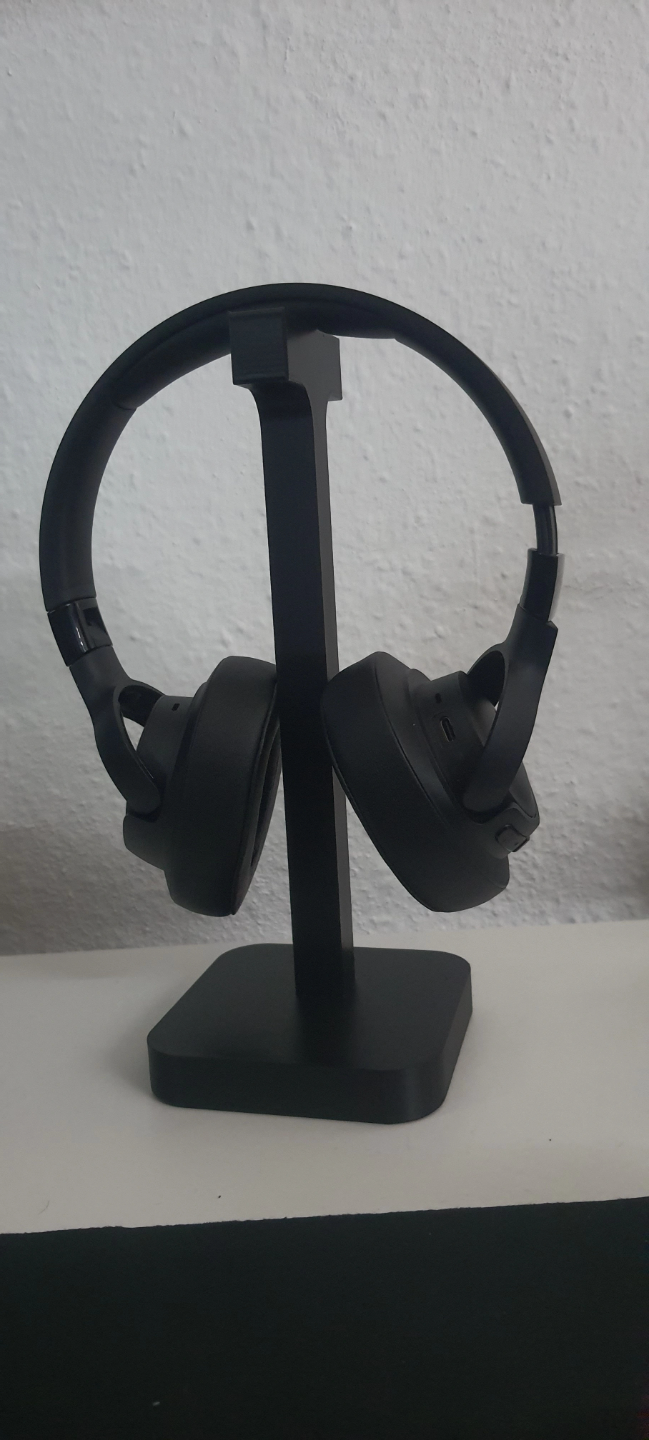 Hörlursställ på skrivbord bredvid skärm och skrivbordslampa
