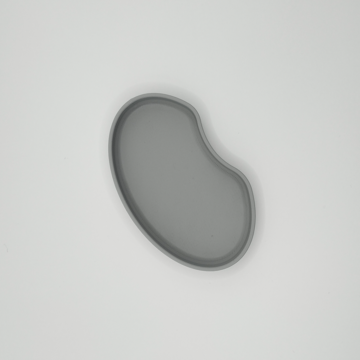 Detalj av njurformad brickas mjuka kant och minimalistiska siluett