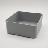 Vit minimalistisk fyrkantig skål på ett soffbord i trä med fjärrkontroll och nycklar