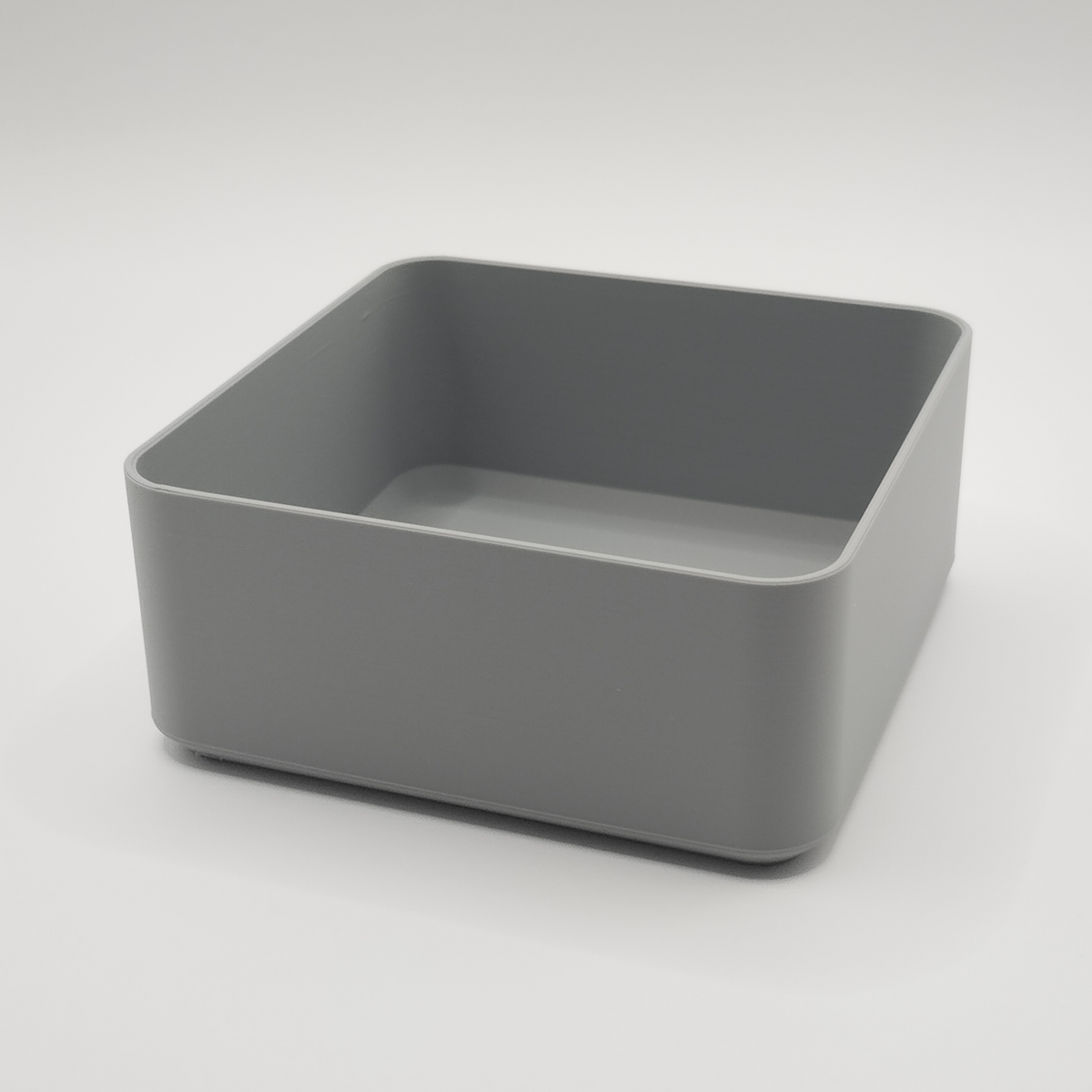 Vit minimalistisk fyrkantig skål på ett soffbord i trä med fjärrkontroll och nycklar