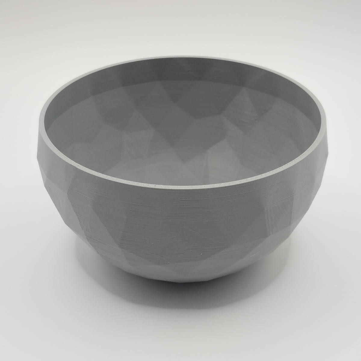 Low poly-designskål på en minimalistisk hylla med neutral inredning