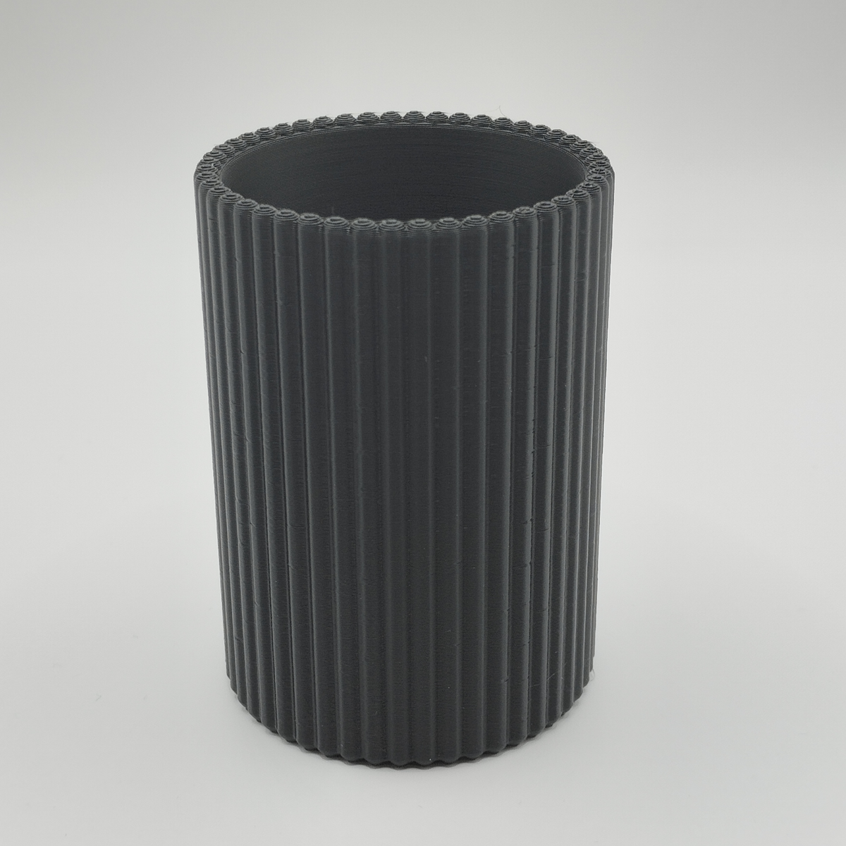 Räfflad pennhållare på ett skrivbord med pennor och minimalistisk arbetsplats