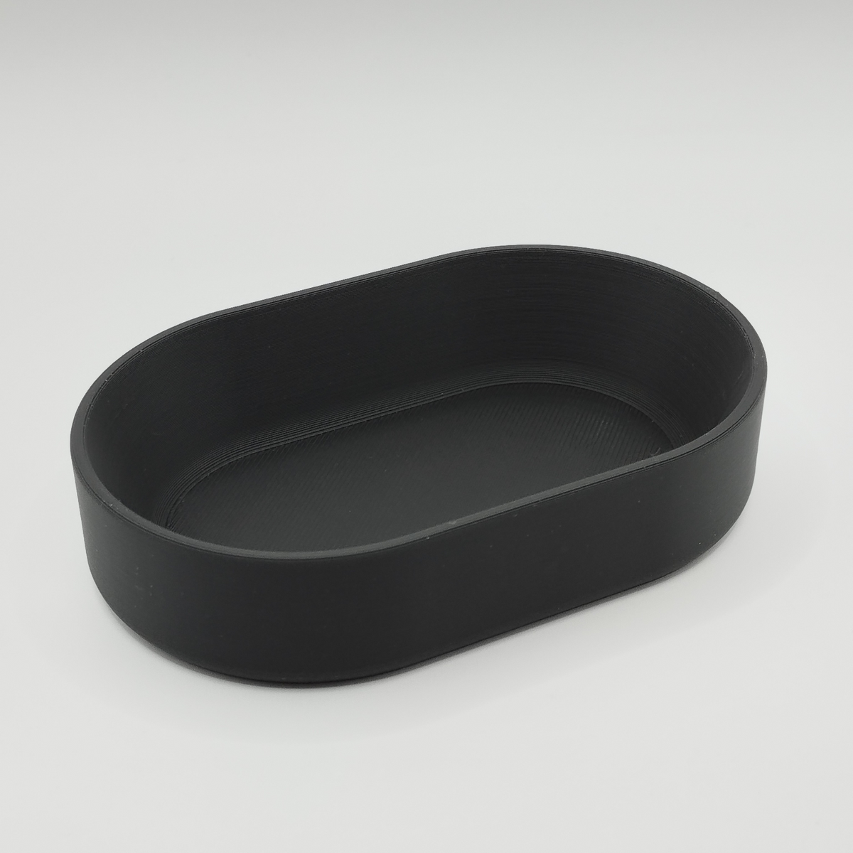 Oval bricka på ett hallbord med nycklar och mynt samt minimalistisk inredning