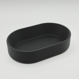 Oval bricka på ett hallbord med nycklar och mynt samt minimalistisk inredning