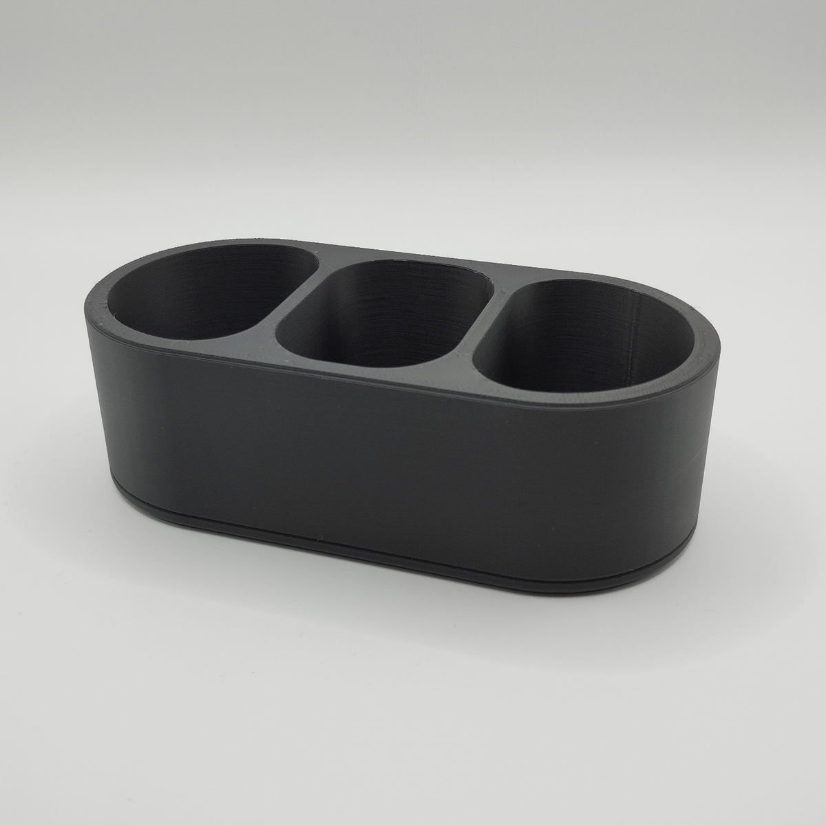 Minimalistisk fjärrkontrollshållare på ett soffbord i trä med fjärrkontroller och småsaker