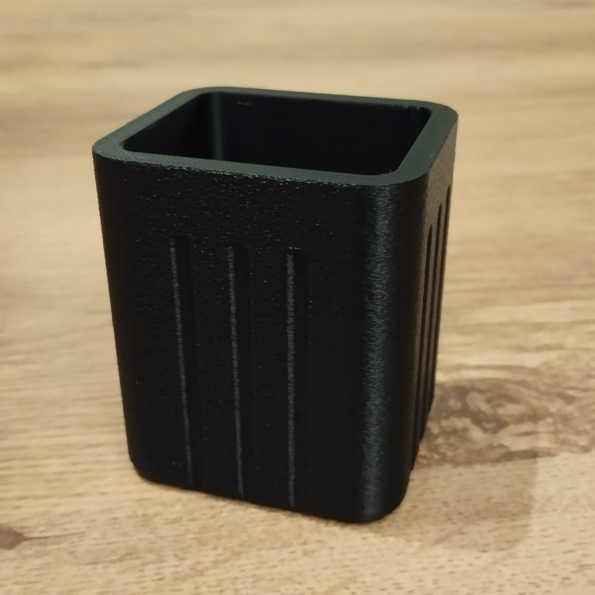 Närbild av en minimalistisk fyrkantig pennhållare med räfflade sidor