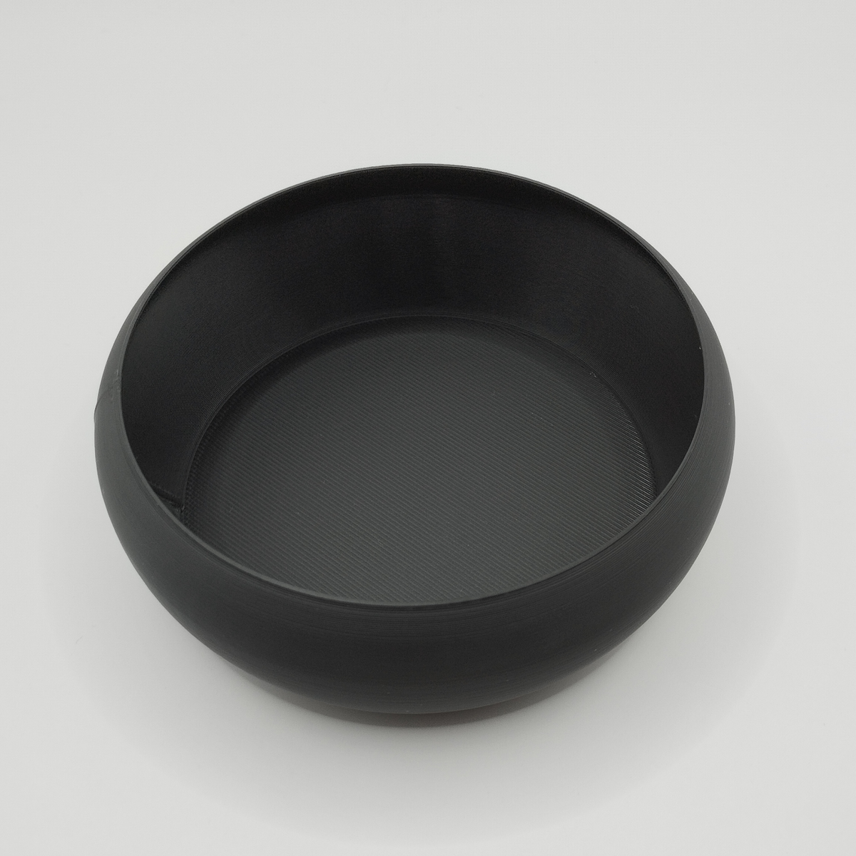 Minimalistisk nyckelskål på en trähylla med nycklar och mynt bredvid en växt