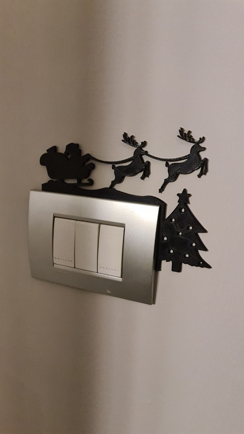 Jultomte i släde med renar som siluett ovanför ett eluttag