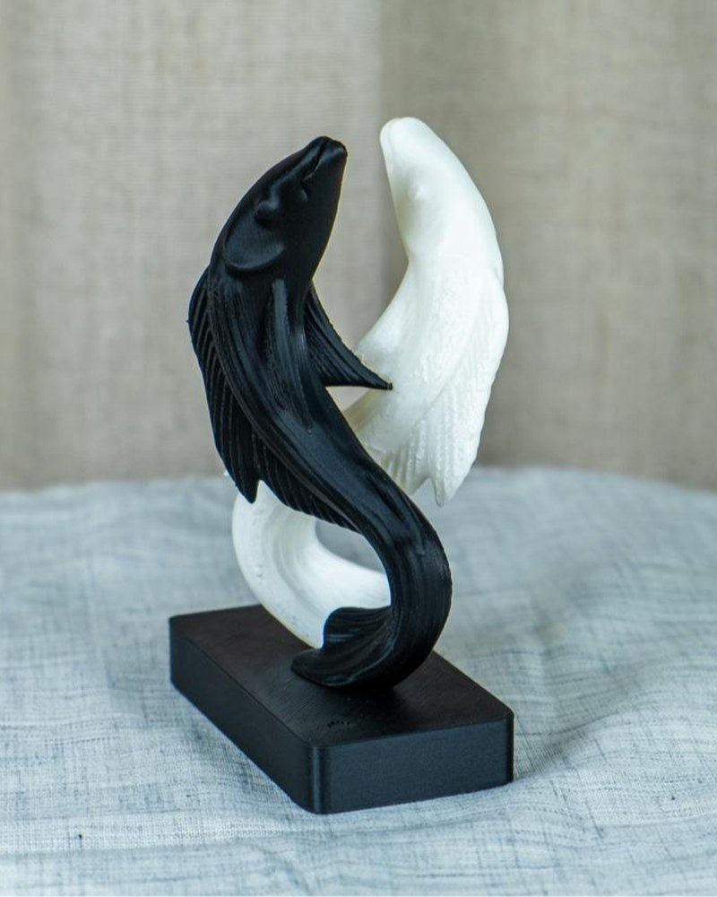 Yin och yang-koiskulptur i svart och vitt med detaljerade fenor och fjäll, framifrån