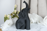 Svart modern elefantskulptur på ett minimalistiskt skrivbord bredvid ett ljus och en liten växt