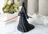 Närbild av en kvinnlig samurajfigur med veckad dräkt och svärd