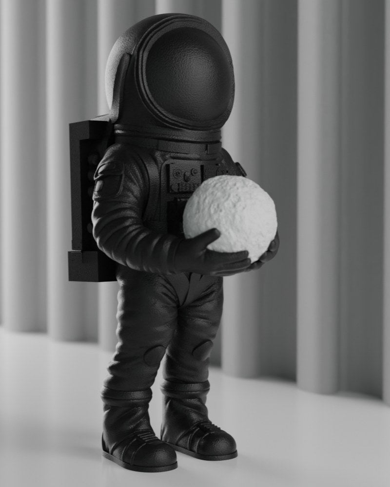 Mattsvart astronautskulptur på ett vitt skrivbord, rymddekoration, framifrån