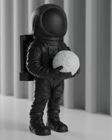 Mattsvart astronautskulptur på ett vitt skrivbord, rymddekoration, framifrån