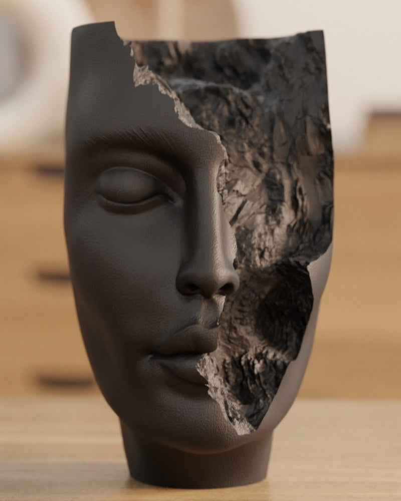 Närbild av den abstrakta ansiktsskulpturen The Hollow Face med slutna ögon och organiska sprickor