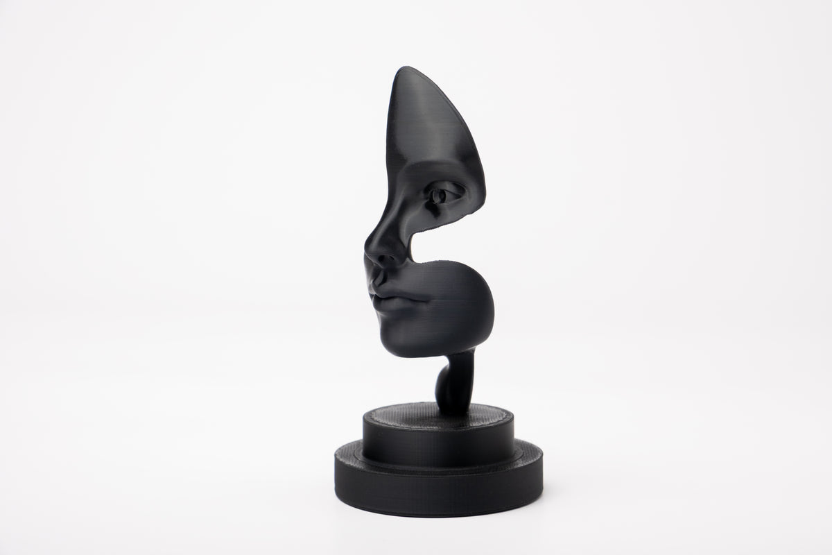 Note of Emotion – abstrakt svart skulptur på en minimalistisk hylla med böcker och ett ljus